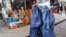 Afghan women wearing burqas walk down a market street in Kabul.