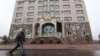 A man walks in Almaty, Kazakstan, walks past the office building of the Nur Otan ruling party, which was damaged during mass protests triggered by a fuel price increase in January. 