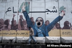 On January 3, a man walks past a mural on the wall of current Ministry for the Promotion of Virtue and Prevention of Vice that says "Brave" at the top and "Afghan women no longer silent" below.