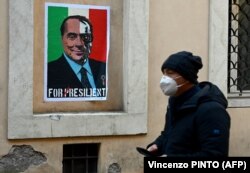 Një qytetar kalon pranë një posteri të përdhosur të ish-kryeministrit italian, Silvio Berlusconi, në Romë. Janar, 2022.