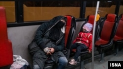 A homeless mother and child bunk down for the night on a public bus in Tehran. 