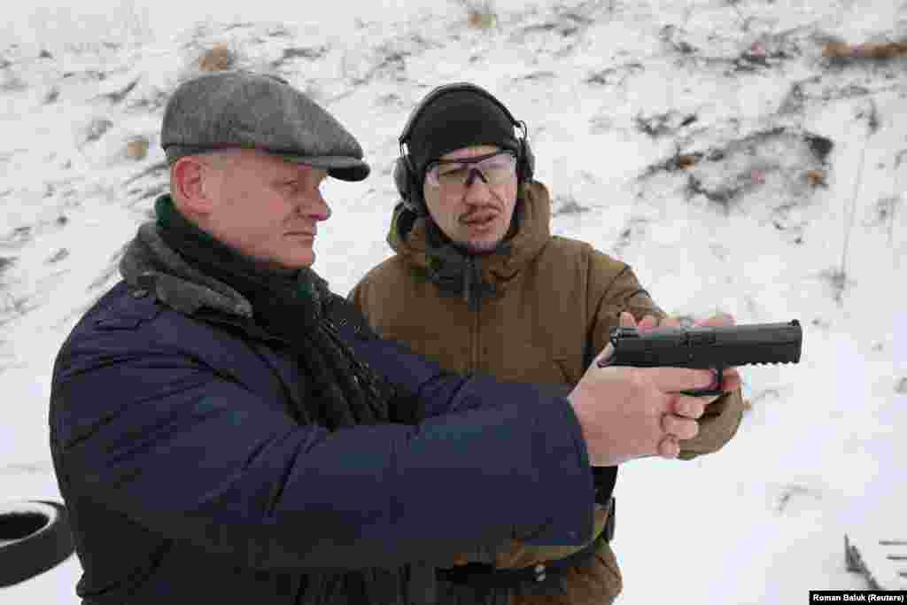 A man handles a pistol during a military training session for workers of &quot;essential city industries and services&quot; near the western Ukrainian city of Lviv on January 25.&nbsp;