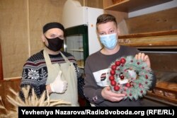 Олег Огієнко та Твіс Лакман показують різдвяний вінок, який крамниці подарувала одна з покупців