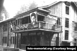 Милиционерски участък в трудов лагер в Томск през 1934 г. На балкона са портретите на съветския лидер Йосиф Сталин (вдясно) и Феликс Дзерджински, който пряко ръководи репресиите, известни като "Червения терор". Един от лозунгите гласи: "Само в страната на Съветите можеш да промениш човек чрез труда".