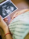 Žena gleda fotografiju bebe sa ultrazvuka, 2021.