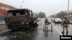 Bezbednosne snage čuvaju stražu u blizini zapaljenog kamiona dok proveravaju vozila u najvećem kazahstanskom gradu Almati. (8. januar 2022)