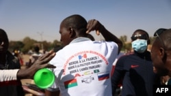  Демонстрант демонстрира тениската си с антифренски лозунги и с флаговете на Буркина Фасо и Русия с две стиснати ръце сред тях, 25 януари 2022. 