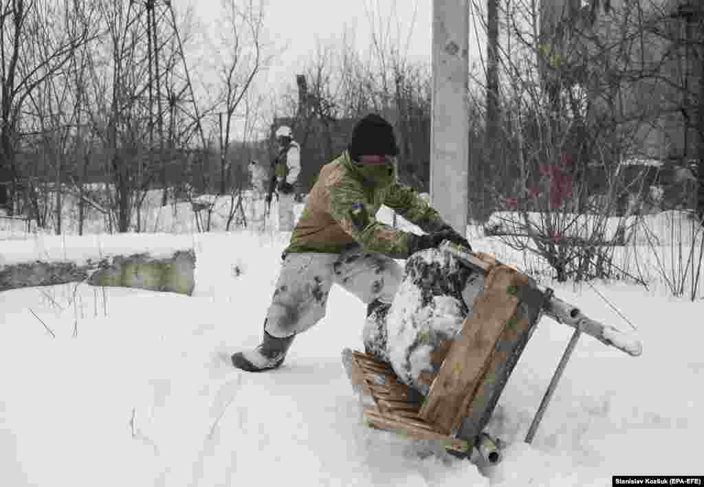 A Ukrainian soldier transports firewood at a frontline position near the village of Avdiyivka on January 25.&nbsp;