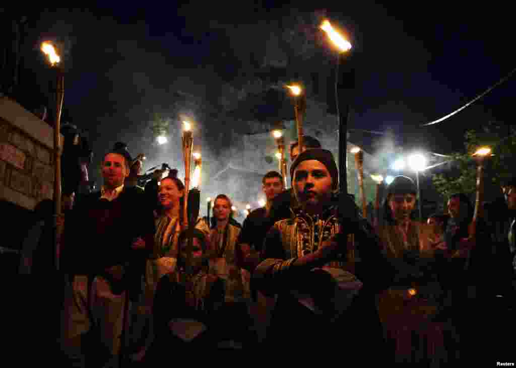 People in folk costumes hold torches during a procession the night before the wedding in the village of Galicnik.