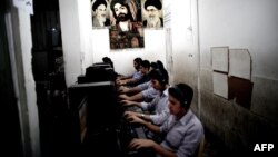 Young Iranians play at a game net arcade decorated with carpets with portraits of the late founder of Islamic republic, Ayatollah Ruhollah Khomeini, Supreme Leader Ayatollah Ali Khamenei, and an Islamic religious portrait, in the city of Qom.