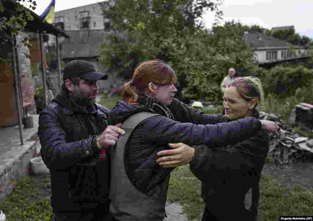 Separated since the start of the Russian invasion, Maria (center) embraces her parents Maryna and Oleksandr in the newly liberated city of Izyum.