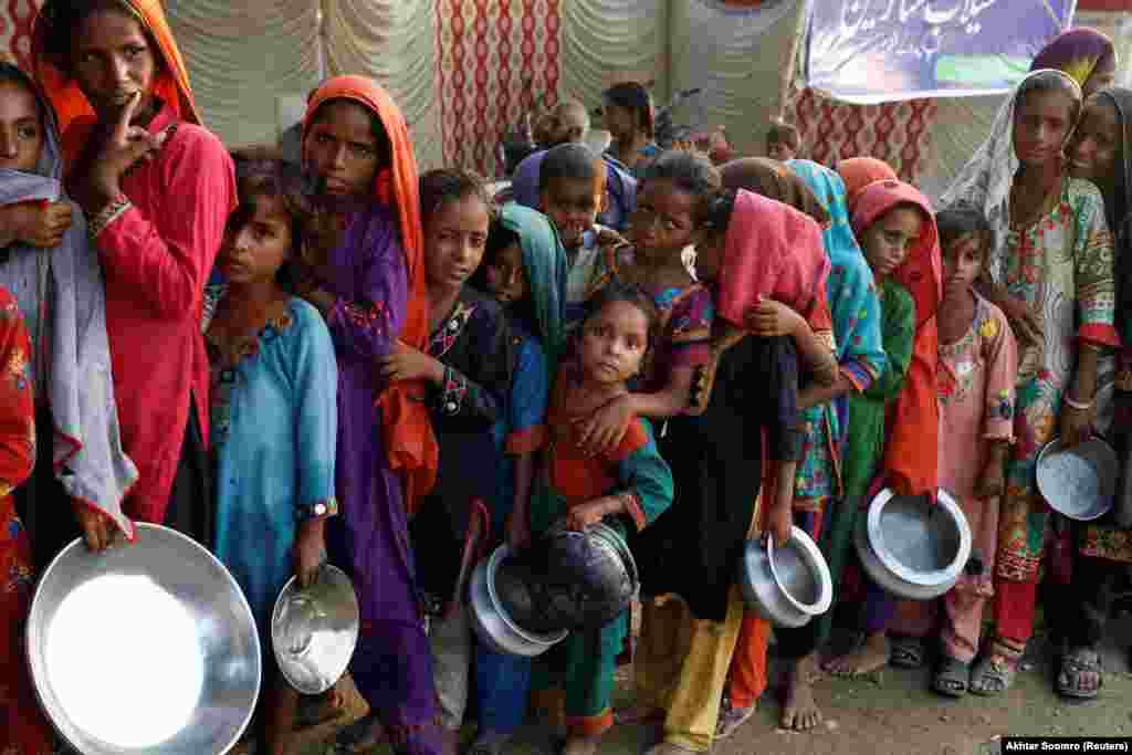 Az árvizek miatt menekülésre kényszerülők állnak sorba ételosztáskor egy ideiglenes táborban a Szindh tartománybeli Sehunban szeptember 14-én