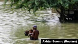 د سیند په سېهوڼ کې یو سړی خپل ماشوم خوندي ځای ته انتقالوي - د سېپټېمبر ۱۳مې انځور.