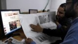 Pakistan -- Pakistani men read a local edition of the International New York Times with a blank space that was supposed to be reporting on the first issue of the French magazine Charlie Hebdo since last week's attack, in Islamabad, January 14, 2015