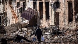 A resident walks in front of destroyed houses in the northeastern Ukrainian city of Trostyanets on March 29.