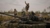 A Ukrainian serviceman takes a selfie photograph standing on a destroyed Russian tank after Ukrainian forces overran a Russian position outside Kyiv on March 31. 
