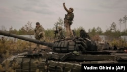 A Ukrainian serviceman takes a selfie photograph standing on a destroyed Russian tank after Ukrainian forces overran a Russian position outside Kyiv on March 31. 