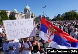 A man holds a banner that reads, ''Rio Tinto go away!'' during a protest against pollution and the exploitation of a lithium mine in Belgrade on September 11, 2021.