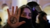 Демонстрант показывает символ мира, нарисованный на ее руке, рядом с сотрудником силовых органов во время антивоенного протеста против вторжения России в Украину в Санкт-Петербурге, Россия, 2 марта 2022 года