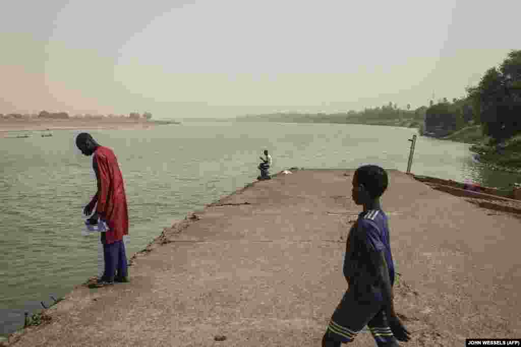 Люди смотрят со старого порта на реке Сенегал в Матаме на границе Мавритании и Сенегала, 11 марта 2022 года.