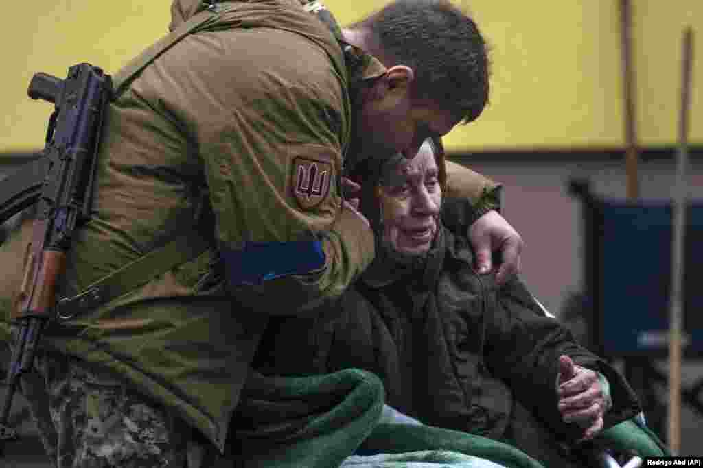 Egy ukrán katona vigasztalja a 82 éves Larisza Kolesznikot, akit Irpinyből evakuáltak