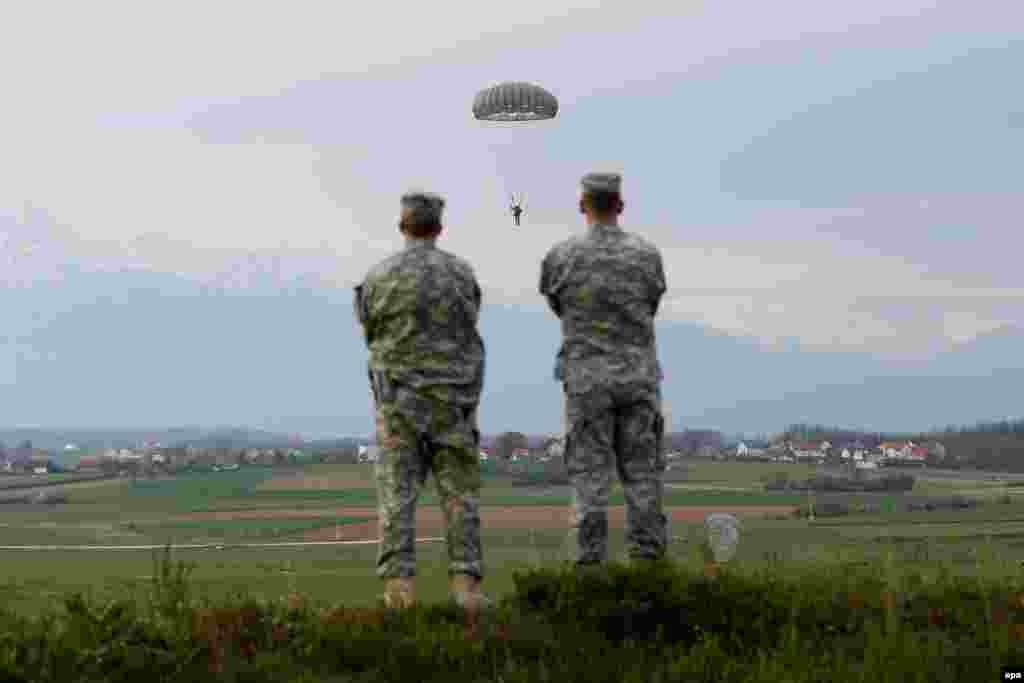 Two soldiers watch as U.S. troops conduct parachute training exercises to keep soldier&#39;s skills fresh at Camp Bondsteel in Kosovo. (epa/Valdrin Xhemaj)