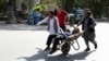 Afghan men carry a wounded man after the second blast in Kabul on April 30