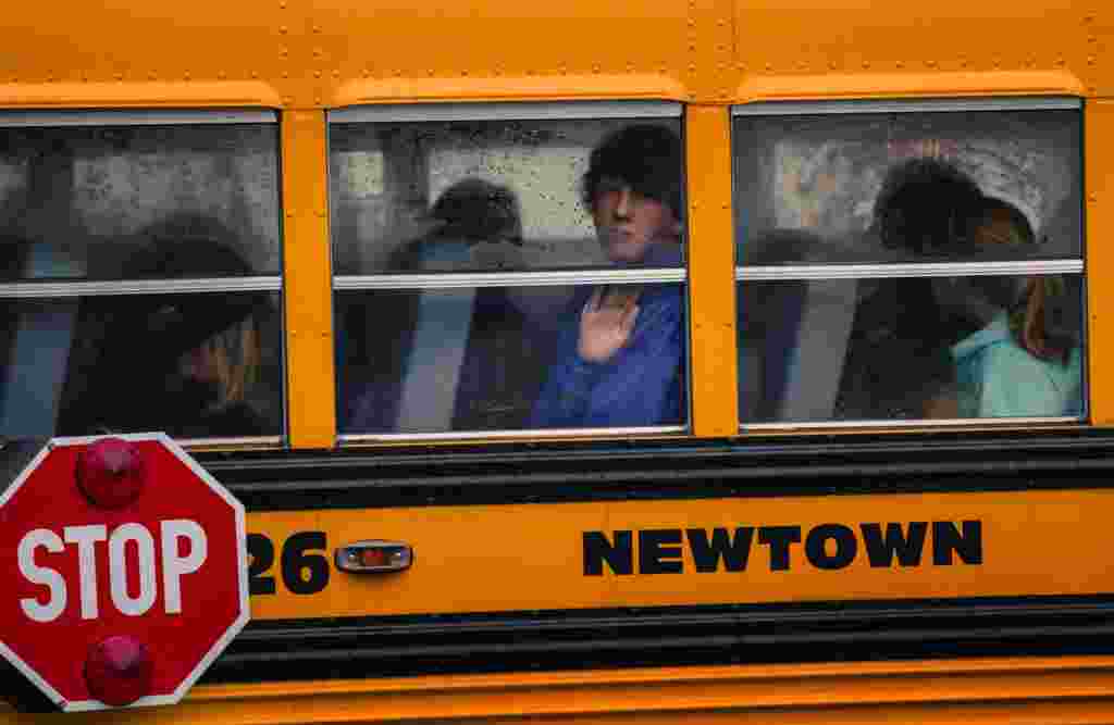 Children look out the windows of a school bus as it pulls into Newtown High School in Newtown, Connecticut. Students returned to school in the shattered Connecticut town on December 18, accompanied by police and counselors to help them cope with grief and fear after a shooting rampage that killed 26 people in the town, 20 of them small children. (Reuters/Lucas Jackson)