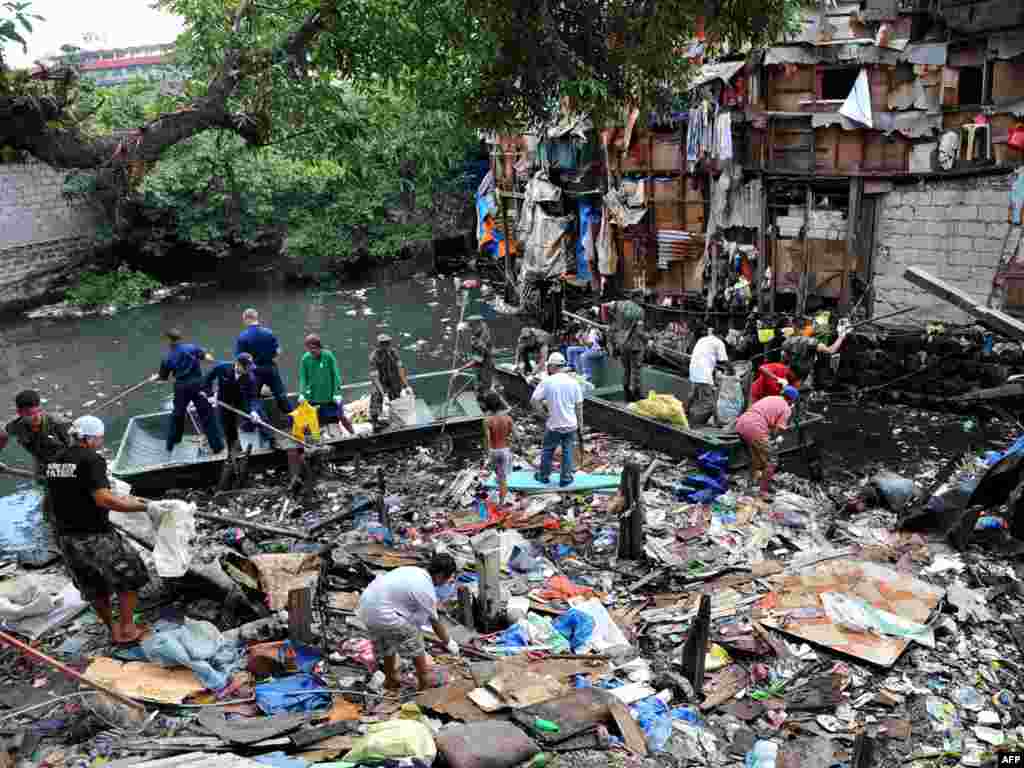 U.S. sailors from the visiting aircraft carrier "USS George Washington," in blue coveralls, join their Filipino counterparts in cleaning a heavily polluted waterway in a Muslim area of Manila on September 6. The carrier is in Manila for a four-day goodwill visit to carry out humanitarian projects. Photo by Jay Directo for AFP