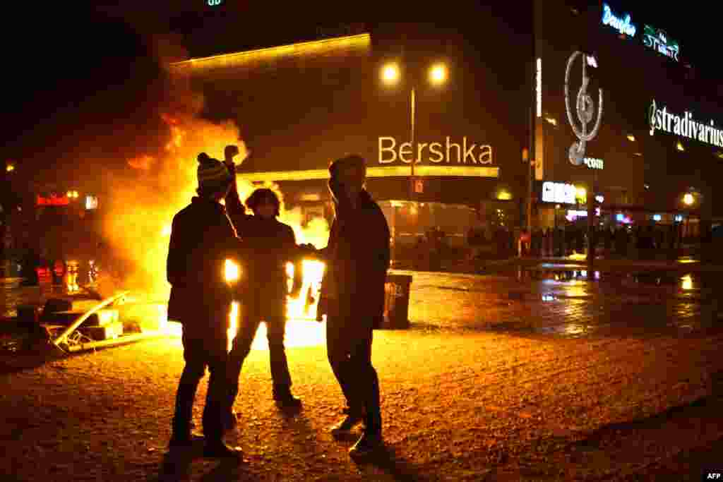Youths stand by a fire lit by protesters after antiausterity demonstrations turned violent in the center of Bucharest on January 15. (AFP/Andrei Pungovschi)