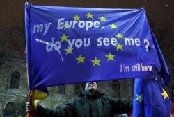 Një person mban në duar në pano ku shkruan: Evropa ime a po më sheh, unë jam ende këtu.