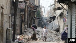 Syria -- Civilians walk past debris from destroyed buildings in the old sector of the northern city of Aleppo, 23Oct2012