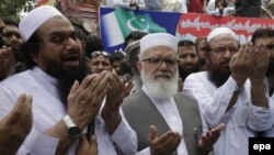 Hafiz Saeed, left, head of the banned Islamic charity Jamat-ud-Dawa, prays during a rally to mark Black Day, in Lahore, Pakistan, on July 19, 2016. 