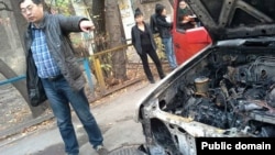 Гражданский активист Ермек Нарымбаев показывает на свою сгоревшую машину. Алматы, 24 октября 2013 года. 