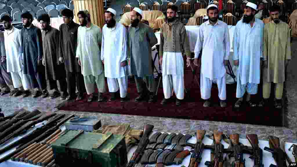 Taliban fighters stand handcuffed near their seized weapons as they are displayed to the media at the governor&#39;s house in Jalalabad. Nineteen Taliban insurgents were arrested by Afghan joint forces during an operation in the Bati Kot District of Nangarhar Province. (AFP/Noorullah Shirzada)