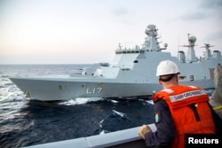 Офицер норвежских ВМС с борта своего фрегата "Хельге Ингстад" смотрит на сторожевой корабль ВМС Дании "Эсберн Снаре". Оба корабля охраняют судно с сирийским химическим оружием