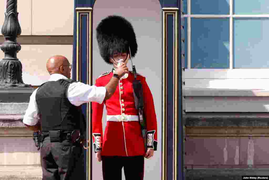 Un membru al Gărzii Reginei primește apă în fața Palatului Buckingham din Londra, Marea Britanie, 18 iulie 2022. Marea Britanie urmează să aibă cea mai călduroasă zi înregistrată vreodată, temperaturile de marți urmând să ajungă până la 42 de grade Celsius.