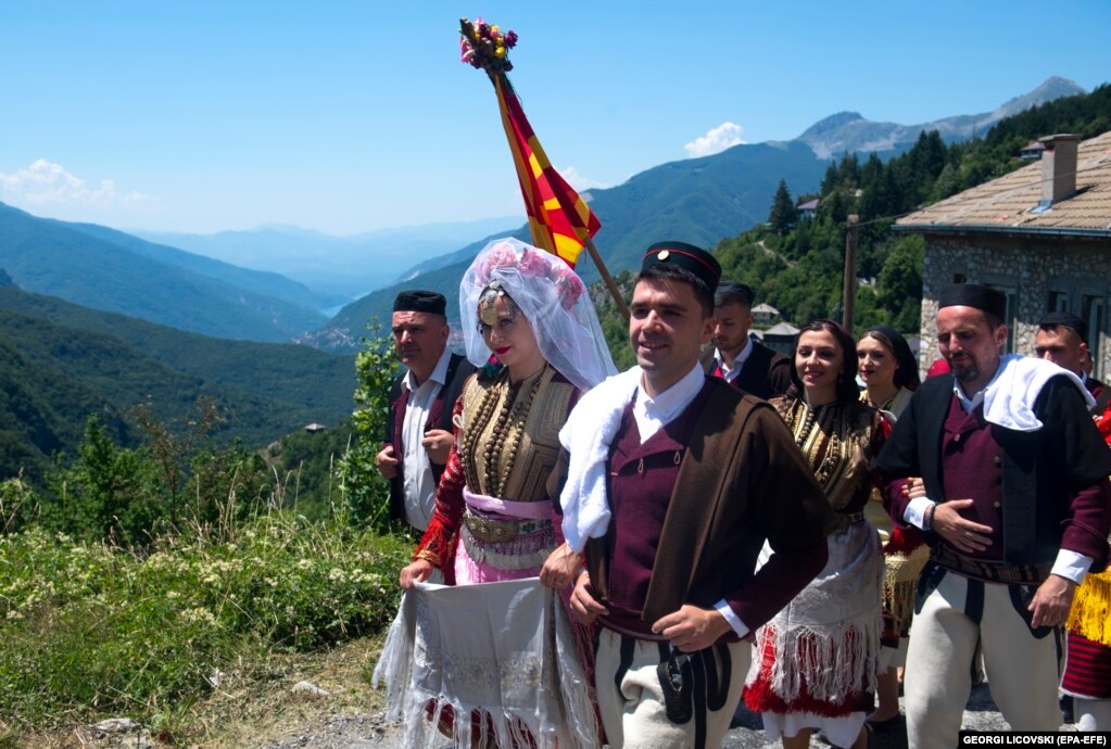 Nusja dhe dhëndri duke ecur së bashku teksa shkojnë në kishën ortodokse të fshatit për ceremoninë e martesës.