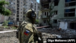 Egy orosz katona járőrözik egy lerombolt lakónegyedben Szeverodonyeck városában július 12-én