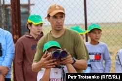 Специалист Казахстанской ассоциации сохранения биоразнообразия Альберт Салемгареев показывает школьникам куланов в Центре реинтродукции АСБК. Костанайская область, 19 июля 2022 года
