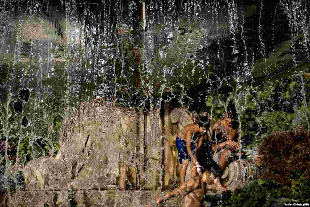 Boys play in a city fountain before sunset in Bucharest.