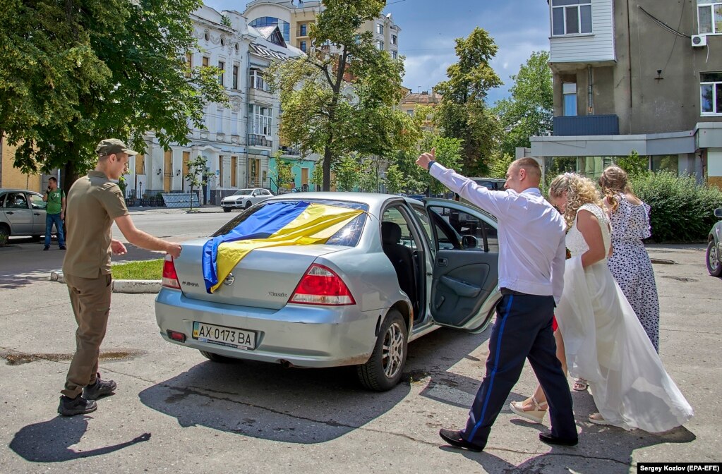 Ushtari i Gardës Kombëtare, Ihor, dhe nusja e tij, Kira, duke dalë nga një  bodrum ku u martuan në Harkiv më 23 qershor. Ceremonitë e martesës në qytetin lindor tani mbahen shpesh nën tokë, si masë mbrojtëse ndaj bombardimeve të mundshme.
