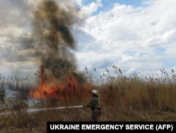Një zjarrfikës duke shuar zjarrin në një fushë të mbjellë në rajonin e Hersonit. 18 korrik 2022