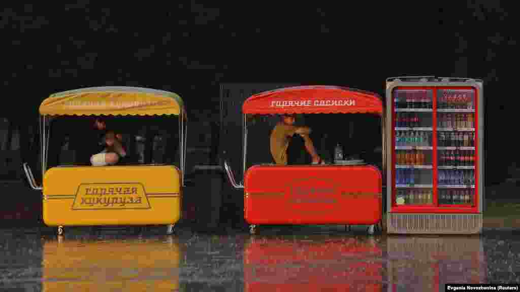 Prodavači sjede na kioscima dok se štite od jake kiše u blizini Sjeverne riječne stanice u Moskvi, Rusija, 25. juli.