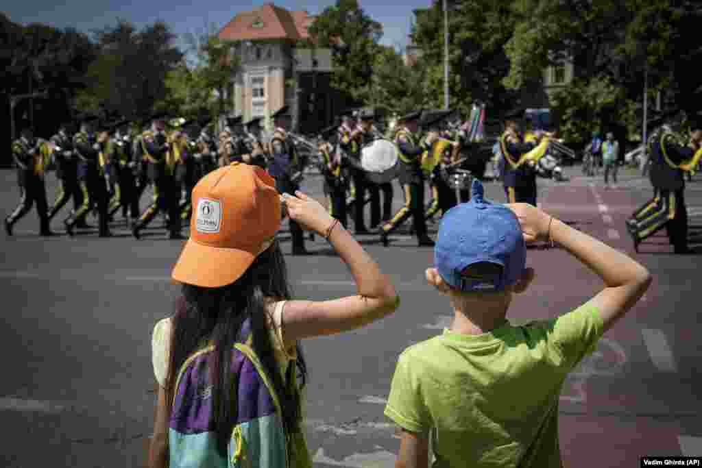 Children playfully salute a military band at the end of a ceremony at the Aviation Heroes monument in Bucharest.
