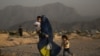Afgán nő gyermekeivel egy temető mellett Kabulban 2022. július 19-én