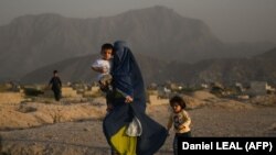 Afgán nő gyermekeivel egy temető mellett Kabulban 2022. július 19-én