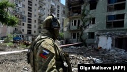 Ruski vojnik patrolira u uništenoj stambenoj četvrti u gradu Severodonjecku, juli 2022. godine