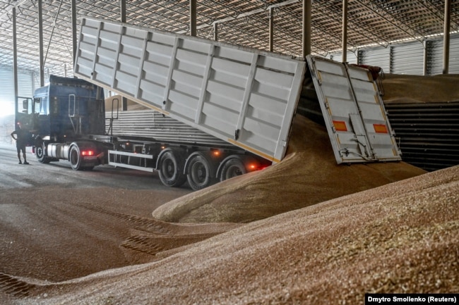 Një punonjës shkarkon grurin e korrur brenda një depoje në rajonin Zaporizhja, Ukrainë, korrik 2022.