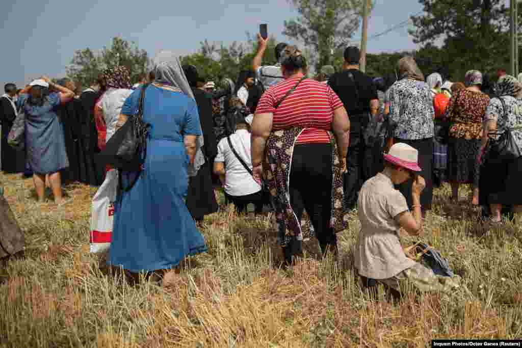 O femeie îngenunchează alături de o mică mulțime care s-a adunat lângă Drăgănești-Vlasca, în sudul României, pentru a se ruga pentru ploaie, pe 24 iulie.